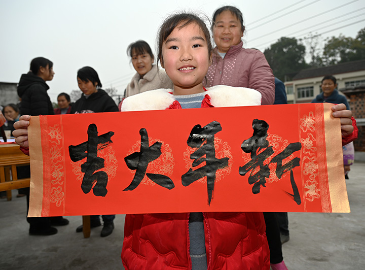 6)在内江市东兴区椑木镇沙石村，一名小朋友在展示刚刚领到的春联（横批）.jpg