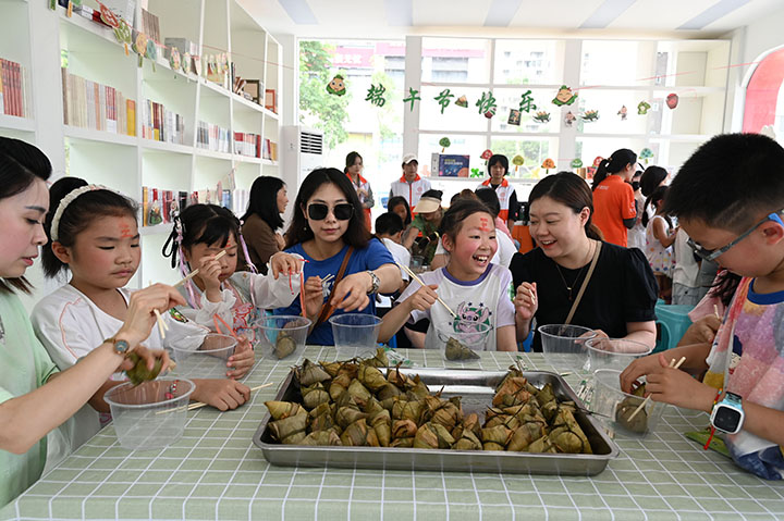 图1   2023年6月18日，四川省内江市东兴区新时代文明实践中心，小朋友和家长一起品尝自己亲手包的粽子。.jpg