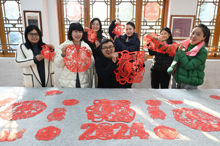 图2  2023年12月27日，在四川省内江市东兴区东兴老街，非遗传承人李有生（中）带领剪纸爱好者体验剪纸迎接新年。.JPG