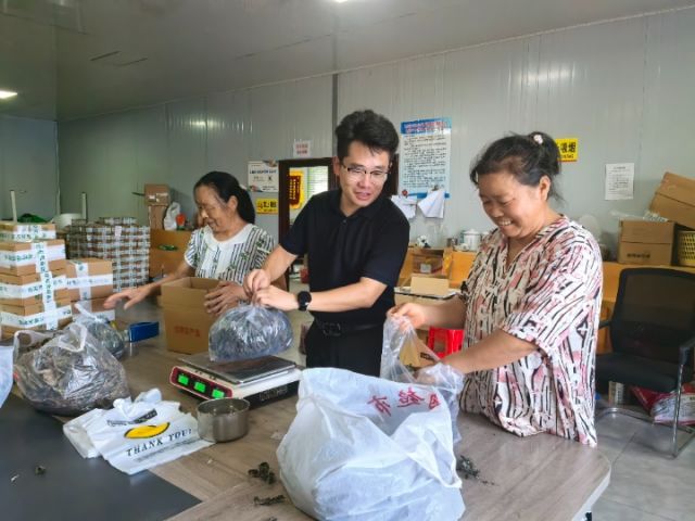 图3  关祖苹正在和村电商中心工人一起称重打包“土货”。潘政吉  摄.jpg