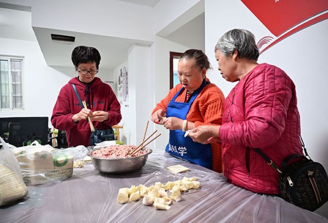 图3  志愿者与老人一起包抄手.jpg